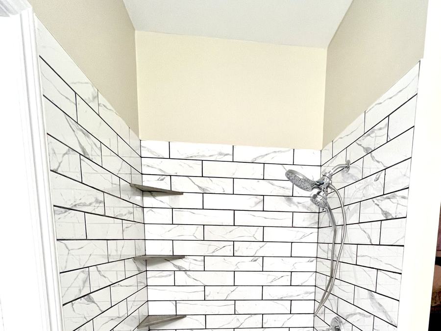 Tiled shower with marble-look subway tile and built-in shelves