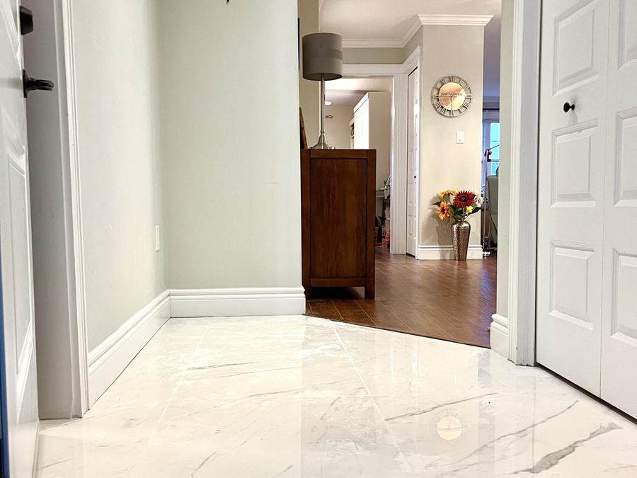Large-format marble-look tile floor in a hallway meeting hardwood