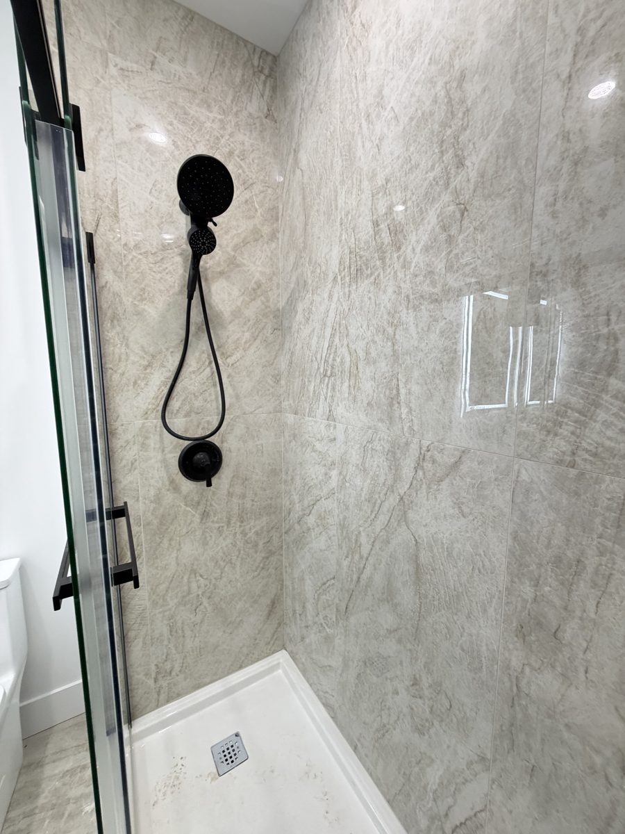 Tiled shower walls with black fixtures, by High-5 Renovations