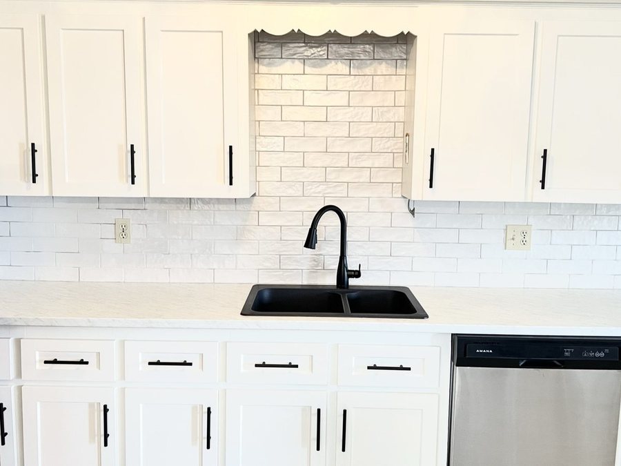A white subway tile backsplash by High-5 Renovations